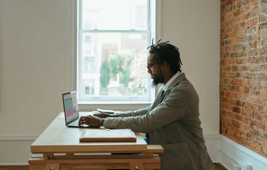 a person sitting at a desk with a laptop and papers